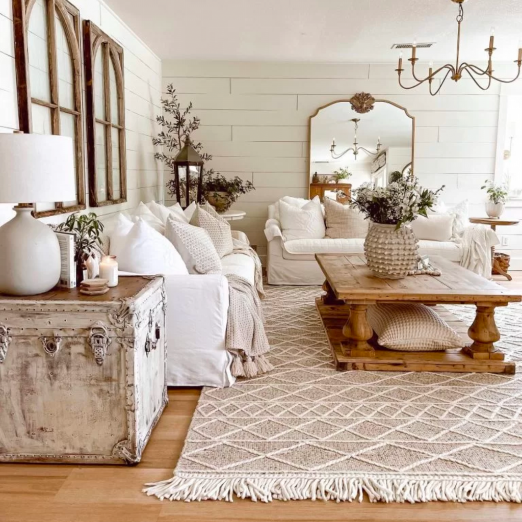 Farmhouse design style living room with a white sofa, rustic wood coffee table and vintage looking end tables. 