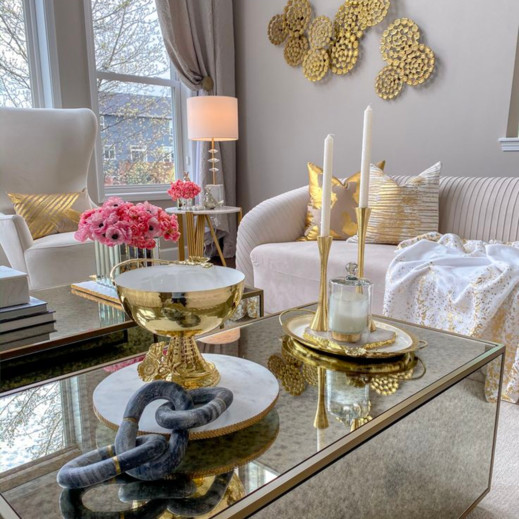 Glam design style living room has mostly ivory upholstery paired with mirrored case goods and brass wall decor.  Plenty of accessories installed. 