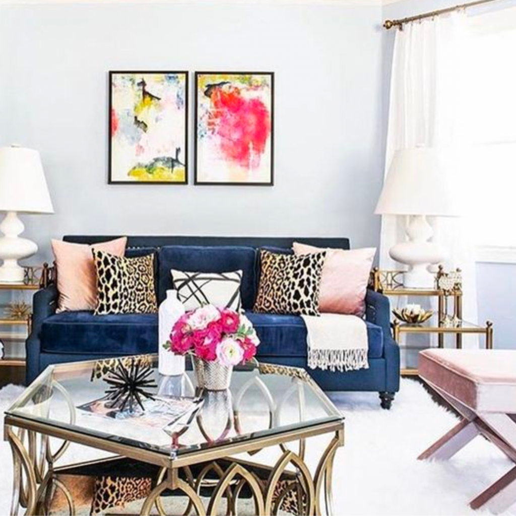 Colorful living room with patterns and textures artfully mixed and matched.  Blue sofa has cheetah print and blush color throw pillows.  Coffee table is brass.