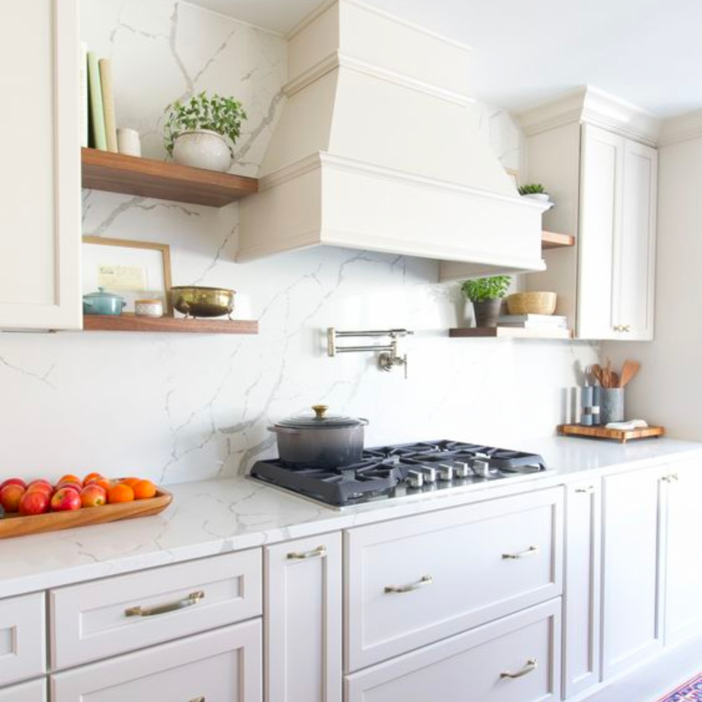 Another interior design trend to stop is an all white kitchen designed with open shelving units flanking the hood above the stove.  All cabinetry is shaker style with brass hardware.