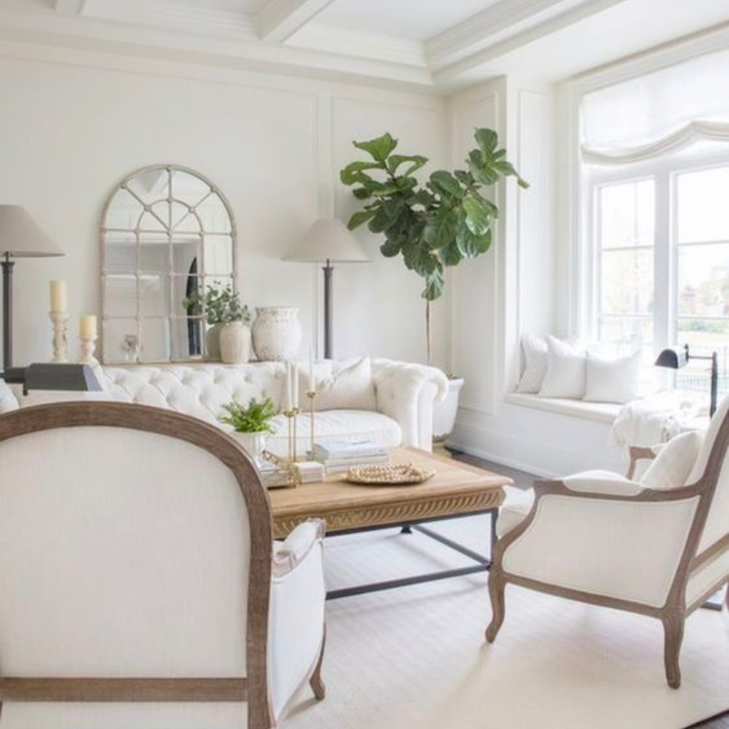 Interior design trends to ditch include all white living room.  Sofa is plush and tufted with white throw pillows.  Armchairs are also white with white throw pillows. 